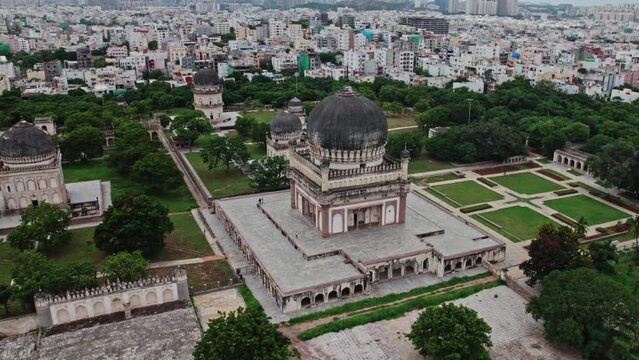 areal drone shot of Mohammad Quli Qutub Shah tomb at Qutub Shahi Tombs, hyderabad, telangana with crowded buildings at the background