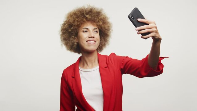 Curly Woman in Red Suit Making Selfie on White Background