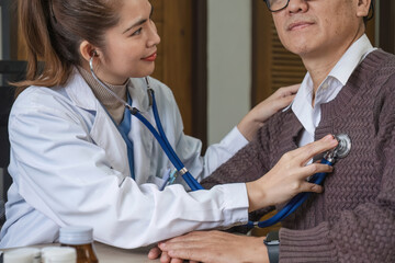 The female doctor in charge holds a stethoscope and listens to the patient. Doctor checking heartbeat examining retired elderly man at home Senior heart disease, health checkup concept health care