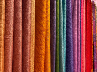 Colourful batik cloth hanging neatly on the display of a boutique