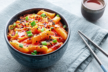 Rabokki, tteokbokki or topokki with ramen, Korean street food, spicy rice cakes in red pepper gochujang sauce, with a drink and chopsticks