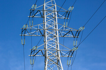 Electrical tower with voltage transmission wires against the background of blue sky. High voltage tower. power line support with wires for electricity transmission. Energy industry.