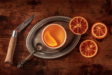 Orange tea with fresh and dried oranges on a vintage tray on a dark rustic wooden background, shot from the top