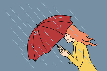 Woman with umbrella rushes home during rain and storm caused by sudden cold snap in autumn and climate change. Girl with umbrella suffers from precipitation and is afraid of getting wet