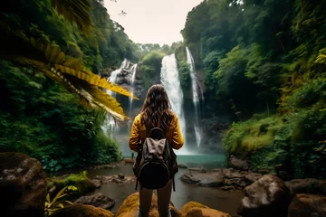 Tuinposter Woman seen from behind in paradise waterfall scenery © Ungrim