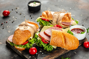 Tasty sandwich salami, tomato, lettuce and cheese on a dark background. top view. place for text