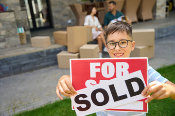 Smiling boy holding for sale, sold signs in his hands