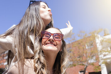 Two young women on top of each other celebrating. Concept travel, freedom, emotion, graduation,...