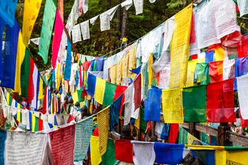 Colorful prayer flags on a bridge at Burning Lake a religious site in Jakar, Bumthang Valley,...