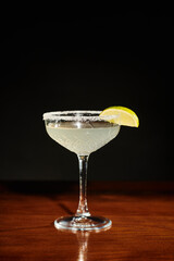 full glass of delicious esthetic margarita with lime slice on black background, concept