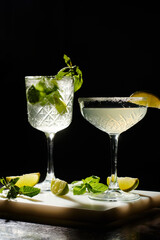 two esthetic cocktails decorated with mint and lime slices on black backdrop, concept
