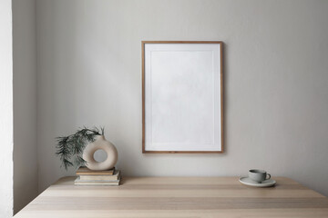 Christmas decorated interior. Modern vase on old books with pine tree branches.Cup of coffee on beige table.Wooden picture frame mockup. White wall background. Minimal modern Scandinavian home.