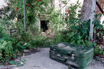 Fototapeta na wymiar old suitcase against the background of a destroyed house in an abandoned city in Ukraine