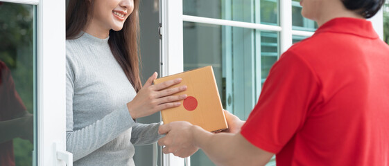 Happy smiling woman receives boxes parcel from courier in front house. Delivery man send deliver...