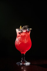 sophisticated berry blues cocktail with blackberry garnishing on black background, concept
