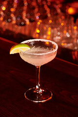 freshening ice cold margarita drink decorated with lime slice on bar counter, concept