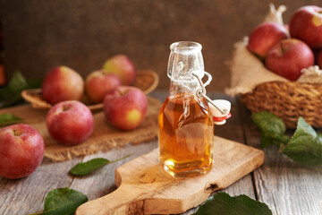 Apple cider vinegar in a glass bottle with fresh red apples