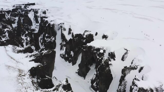 Drone shot circling around a snowy gorge, cloudy winter day in Iceland