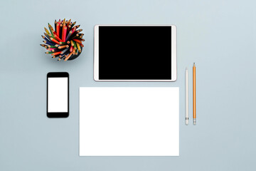 A tablet, a stylus, a simple pencil, a phone, and a blank sheet of paper on a table. A place for...