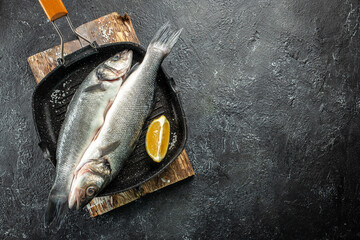 Fresh raw seabass fish on a dark background, Long banner format. top view