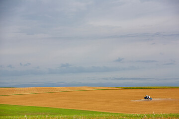 Obraz premium open landscape with large fields and tractor spraying in the north of france