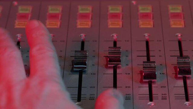 Recording studio mixing desk sliders being adjusted from a straight on above angle.