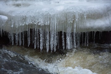 Detail of icy river in winter – closeup shot of icicles.