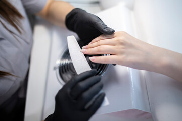 manicurist doing nail polish using file in manicure salon