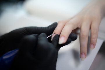manicure master in process of nail treatment in beauty salon