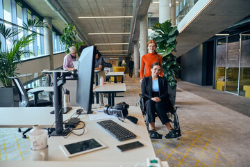 In the contemporary ambiance of a modern startup office, a compassionate businesswoman extends a helping hand to her colleague in a wheelchair, symbolizing inclusivity, teamwork, and the supportive