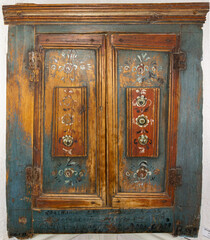 The doors of an old wooden cabinet with drawings and peeling old paint