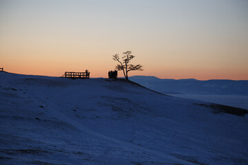 Landscape with an orange sunset over blue snow on Olkhon Island.