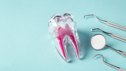 Dental care and treatment concept, tooth with dentist instruments on blue background - obrazy, fototapety, plakaty
