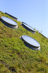 circular shaped skylights on a undulating grass surface, in the background the clear blue sky