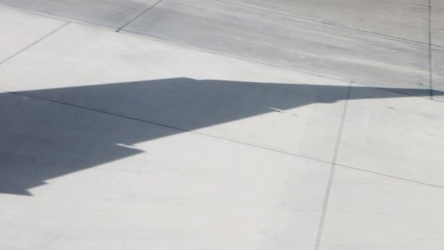 The shadow of the wing of an airplane driving on the runway
