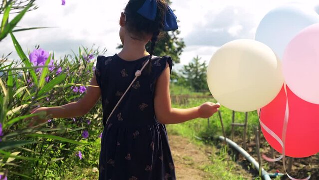 Cute child walking along Beautiful Blossom Ruellia squarrosa while holding balloons.