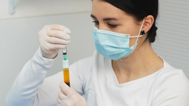Doctor cosmetologist draws blood plasma into a syringe for the plasmolifting procedure, hands in gloves closeup. PRP therapy treatment in beauty clinic. Cure of problem skin.