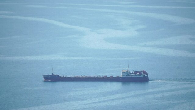 Cargo and dredging industrial ships sailing in to sea horizon. One large cargo ship grain carrier tanker in sea on sunny day. Transport, sea freight, sea transportation of cargo. Aerial view
