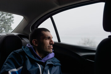 Man emotionally looking at the snowy landscape through the car´s window