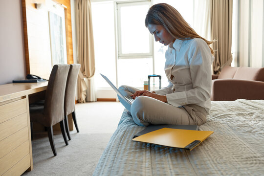 Businesswoman are preparing for a constructive discussion at the business convention. He was sitting on the bed in the hotel and checking financial company files on the laptop.	
