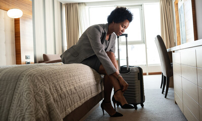 The businesswoman enters her hotel room, takes a seat onto the hotel bed. The comfort of the room...