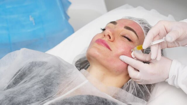 Top view medium close-up shot of platelet rich plasma face injections procedure. PRP Therapy in beauty salon. Young brown-haired female Caucasian patient.