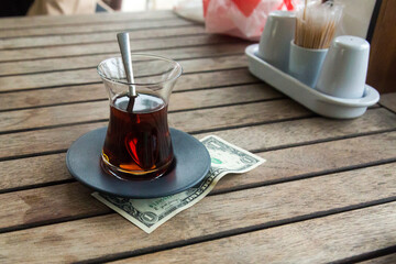 Money left to waiter in a cafe as a tip. Dollar under a cup for a tip to the waiter.