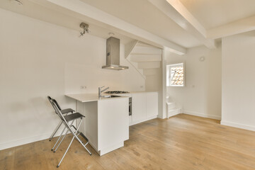 Fototapeta na wymiar a kitchen and dining area in a room with white walls, hardwood flooring and an open door leading to the living room