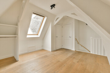 an empty room with wood flooring and skylights on the top of the attic loft windows are visible in the photo
