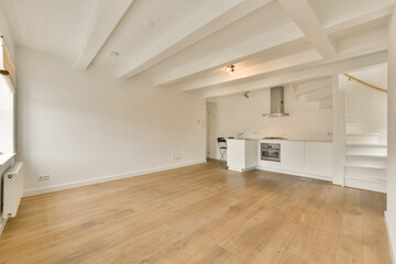 an empty living room with wood flooring and white painted walls in the corner to the kitchen is on...