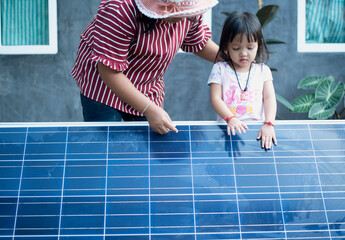 A happy Asian family admires the solar panels they just installed at their home.