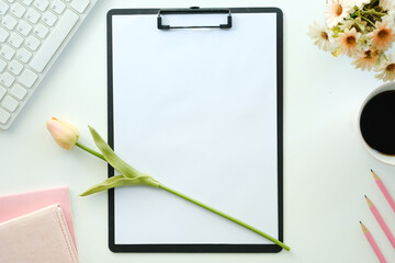 White office desk table with blank notebook, computer keyboard and other office supplies. Top view with copy space, flat lay.