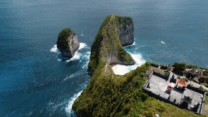 Tourists pilgrimage to ancient temple on top of cliff near Kelingking beach on tropical island Nusa Penida Bali.