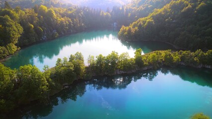 Mountain deciduous forest with calm water in the lake at sunrise. Landscape in summer to early...